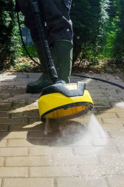 Dışarıdaki veranda fayanslarının üzerinde döner basınçlı çamaşır makinesiyle toprağı temizliyorum. Yüksek kalite fotoğraf