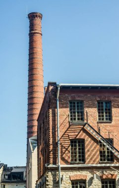 Uzun kırmızı tuğla baca ve mavi gökyüzüne karşı güneş ışığında sanayi binası. Yüksek kalite fotoğraf