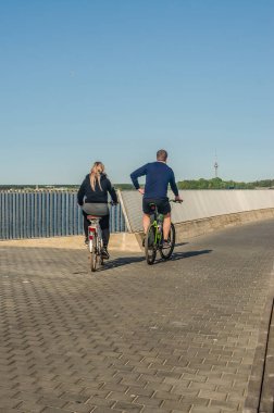Güneşli bir günde, rıhtım boyunca bisiklet süren bir çift. Yüksek kalite fotoğraf