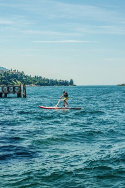 İtalya 'da güneşli bir yaz gününde göl suyunda pedal kullanan bir adam. Yüksek kalite fotoğraf