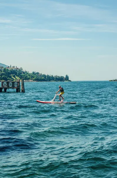 İtalya 'da güneşli bir yaz gününde göl suyunda pedal kullanan bir adam. Yüksek kalite fotoğraf