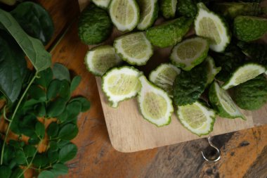 Dilimlenmiş kaffir kireç, ahşap tabak ve ahşap arka plan.