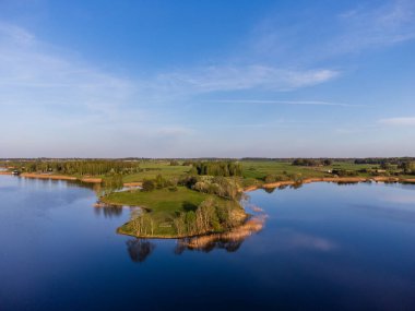 Sakin mavi sularla çevrili sakin bir ada. Barışçıl yeşil bir adanın havadan görünüşü, sakin bir ruh hali, yüksek açılı çekim, kırsal yerleşim, doğa anlayışı ve rahatlama..