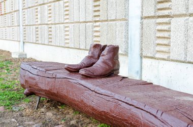 Mysterious european wooden boots resting on a carved bench, unique outdoor urban sculpture. Unmoving, thought-provoking, straight-on angle, outdoor urban setting, artistic representation, rustic atmosphere, surreal concept, storytelling potential. clipart