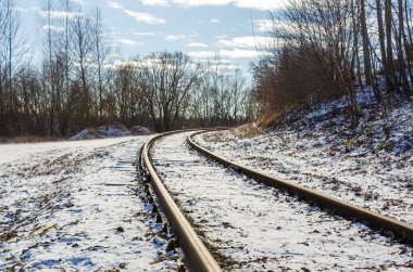 Kış manzarasında esen hafif karla kaplı kıvrımlı demiryolu rayları. Huzurlu hava, karlı arazi, kırsal alan, soğuk hava, kış mevsimi, sakin ve sakin manzara.