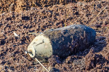 Bahar tarlası kazıları sırasında ıslak toprakta bulunan patlamamış eski bir bomba. Yakın çekim, yatay perspektif, yüksek gerilim havası, bozuk Peatland ortamında açık havada çekilmiş..