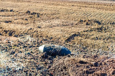 Bahar tarlası kazıları sırasında ıslak toprakta bulunan patlamamış eski bir bomba. Yakın çekim, yatay perspektif, yüksek gerilim havası, bozuk Peatland ortamında açık havada çekilmiş..