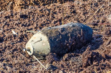 Bahar tarlası kazıları sırasında ıslak toprakta bulunan patlamamış eski bir bomba. Yakın çekim, yatay perspektif, yüksek gerilim havası, bozuk Peatland ortamında açık havada çekilmiş..
