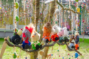 El yapımı Paskalya yumurtası süsleri halk meydanındaki ağaç dallarından sarkan. Ağaçtaki renkli paskalya yumurtalarının yakın çekimi, düşük açı çekimi, neşeli şehir bahar kutlaması.