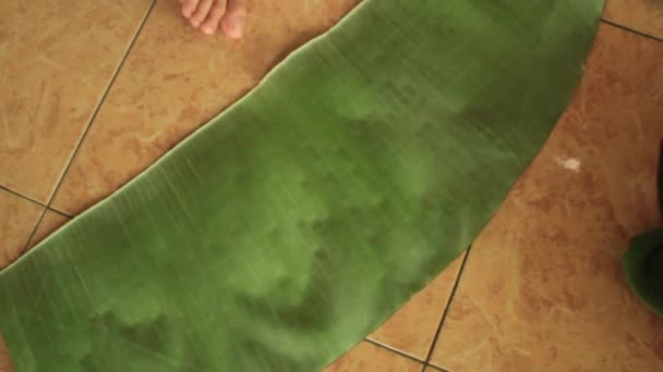 ジャワのスナックの1つである粘着性のある米テープを包むために使用されるバナナの葉をきれいにするプロセス — ストック動画