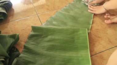 Cava atıştırmalıklarından biri olan yapışkan pirinç bandını sarmak için kullanılan muz yapraklarını temizleme işlemi.