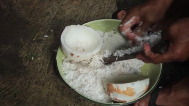 Hindistan cevizi rendesi rendeleyerek hindistan cevizi sütü elde eden bir adam..