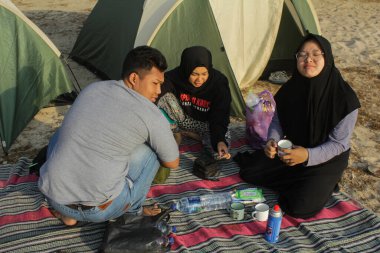 Malang, Doğu Java, Endonezya - 27 Ekim 2019: Çadırın önünde bazı gençler Srau Sahili 'nin kenarında kahvaltı hazırlamak için mutfak aletleri hazırlıyorlar.