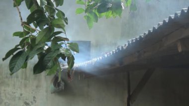 Arka evin asbest çatısından dumanlar yükseliyor.