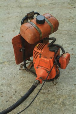 Kullanılmış çim biçme makinesi çimenleri biçmek için kullanılmaya hazır bir evin beton avlusunda duruyor.