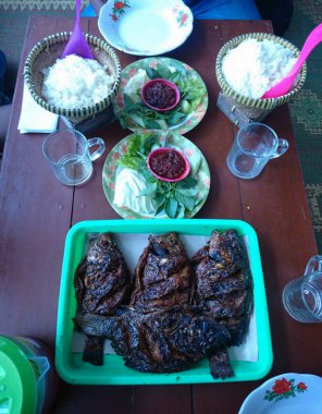 Tatlı soya soslu ızgara tilapia iki sepet beyaz pirinç, baharatlı sambal, fesleğen yaprağı, lahana şeritleri ve biraz yeşil marul yaprağı ile servis edilir..