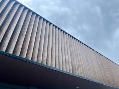 Bulutlu bir gökyüzü arka planına karşı ahşap cephe malzemelerinin olduğu bir binanın alçak açılı görüntüsü