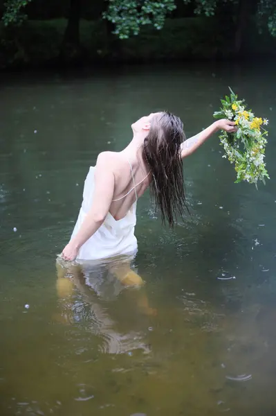 Beyaz elbiseli güzel bir genç kız, sarafan ve çiçek çelengi yazın nehirde ya da gölde