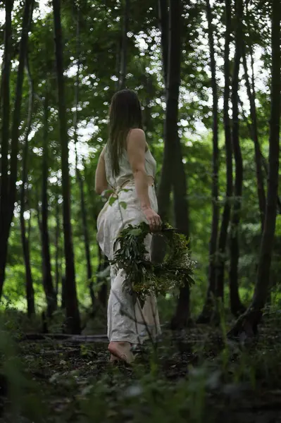 Beyaz elbiseli, uzun saçlı, orman perisi gibi poz veren güzel bir kadın..