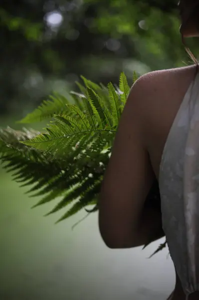 Nehir kıyısında elinde eğreltiotu olan beyaz elbiseli genç bir kız.