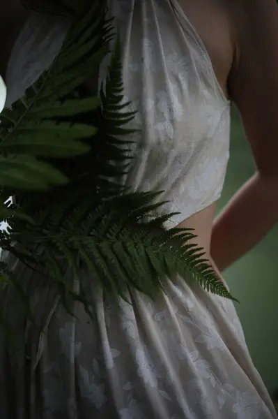 Nehir kıyısında elinde eğreltiotu olan beyaz elbiseli genç bir kız.