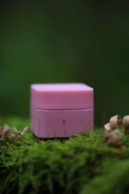 Yaprakların arasındaki bir taşın üzerinde beyaz bir kozmetik tüpü. Doğal bitki kozmetik konsepti. Modelleme. Bulanık arkaplan.