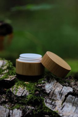 Yaprakların arasındaki bir taşın üzerinde beyaz bir kozmetik tüpü. Doğal bitki kozmetik konsepti. Modelleme. Bulanık arkaplan.