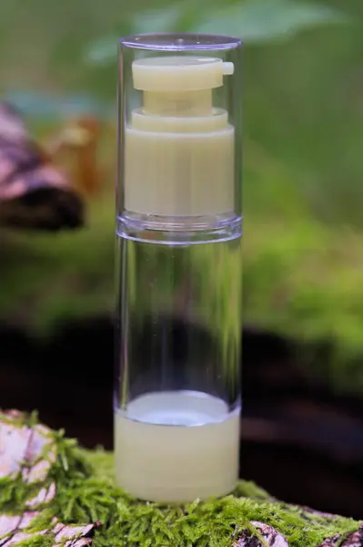 Yaprakların arasındaki bir taşın üzerinde beyaz bir kozmetik tüpü. Doğal bitki kozmetik konsepti. Modelleme. Bulanık arkaplan.