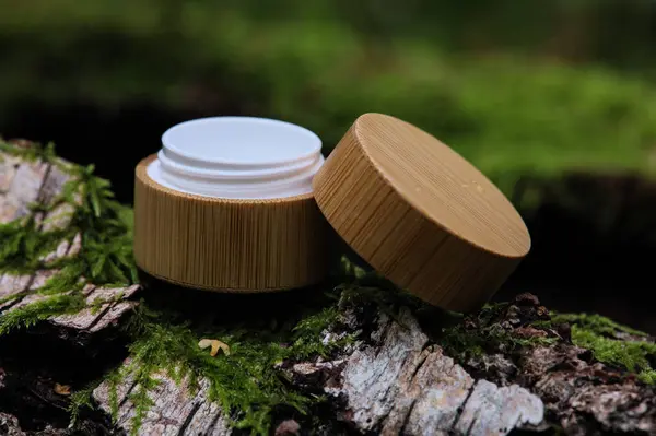 Yaprakların arasındaki bir taşın üzerinde beyaz bir kozmetik tüpü. Doğal bitki kozmetik konsepti. Modelleme. Bulanık arkaplan.