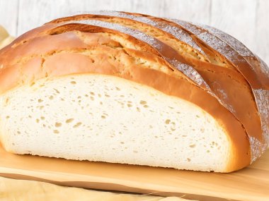 Arka planda ekmek sepeti olan bir somun ekmek kesim tahtasının üzerinde. 