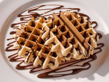 Beyaz arka plan yapay zekasına Belçika Waffle 'ının üstüne çikolata dökmek.