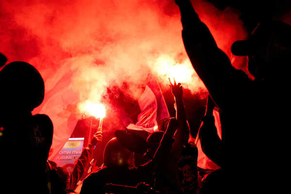 Фанаты "Персиб Бандунг" отмечают победу в BRI Liga 1 2025, наводняя улицы и зажигая вспышки в ярком шоу страсти и гордости.