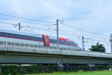 Yüksek hızlı Whoosh treni Endonezya 'nın kırsal kesimlerindeki yüksek raylarda süzülüyor, yemyeşil bir arazi ve mavi gökyüzüne karşı modern ulaşımı sergiliyor..