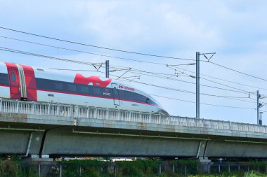 Yüksek hızlı Whoosh treni Endonezya 'nın kırsal kesimlerindeki yüksek raylarda süzülüyor, yemyeşil bir arazi ve mavi gökyüzüne karşı modern ulaşımı sergiliyor..