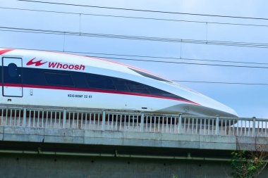 Yüksek hızlı Whoosh treni Endonezya 'nın kırsal kesimlerindeki yüksek raylarda süzülüyor, yemyeşil bir arazi ve mavi gökyüzüne karşı modern ulaşımı sergiliyor..