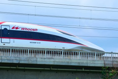 Yüksek hızlı Whoosh treni Endonezya 'nın kırsal kesimlerindeki yüksek raylarda süzülüyor, yemyeşil bir arazi ve mavi gökyüzüne karşı modern ulaşımı sergiliyor..
