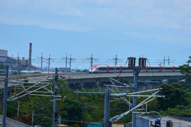 Endonezya 'nın yüksek hızlı treni Whoosh, endüstriyel ve dağ manzarası boyunca yükseltilmiş bir pistte modern demiryolu altyapısını sergiliyor..