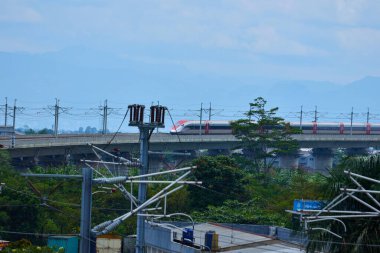 Endonezya 'nın yüksek hızlı treni Whoosh, endüstriyel ve dağ manzarası boyunca yükseltilmiş bir pistte modern demiryolu altyapısını sergiliyor..