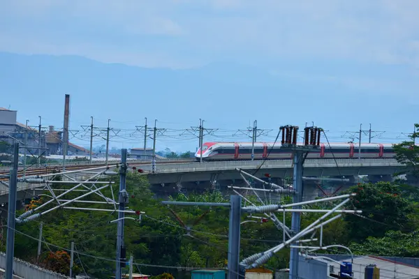 Endonezya 'nın yüksek hızlı treni Whoosh, endüstriyel ve dağ manzarası boyunca yükseltilmiş bir pistte modern demiryolu altyapısını sergiliyor..