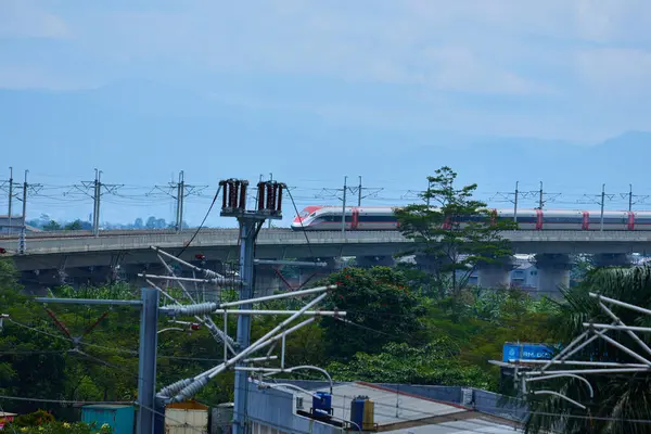 Endonezya 'nın yüksek hızlı treni Whoosh, endüstriyel ve dağ manzarası boyunca yükseltilmiş bir pistte modern demiryolu altyapısını sergiliyor..