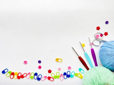 Beyaz arkaplanda iplik topları, örgü kancaları, makas ve dikiş izleri var.