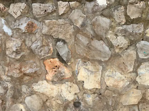 Bu resim, doğal kaya duvar dokusunun detaylı bir yakın çekimini gösteriyor. Yüzeyde karmaşık desenler, dokular ve doğal kaya oluşumlarının tipik renkleri bulunur. Şekillerdeki çeşitlilik ve