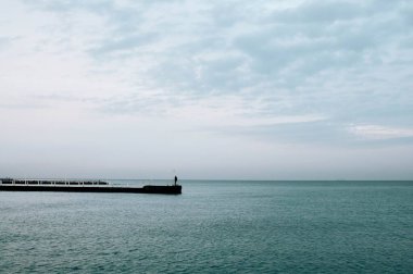 a man walks along a wooden pier that leads into the Black Sea in Odessa. High quality photo clipart