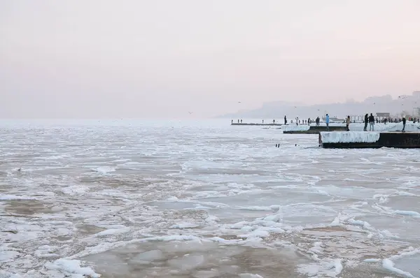 stock image Snow-covered Black sea shore at sunrise.Snow, ice, frozen water. Soft sunlight. Picturesque winter scenery. Seasons, nature, environment, climate change, global warming themes