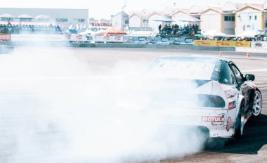 Yarış arabası hız yolunda sürükleniyor, profesyonel sürücü yarış pistinde dumanla sürükleniyor, soyut doku ve arka plan siyah lastik izleri asfalt yolda kayıyor.