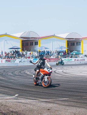 Virajlı yolda kırmızı spor motosiklet kullanan siyah üniformalı bir bisikletçi.