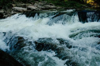 A beautiful view of water flowing at a high rate over bedrock forming waterfalls on the way down the mountain. High quality photo clipart