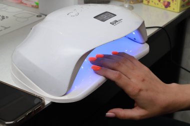 Manikürcü, manikürcü. Beyaz havluyla kuaförde saydam tırnak cilası boyuyor. Yüksek kalite fotoğraf