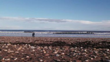 İnsansız hava aracı çok alçaktan uçuyor, insanlar yanından geçerken yanlamasına sahilde uçuyor. Durham ilçesi, İngiltere