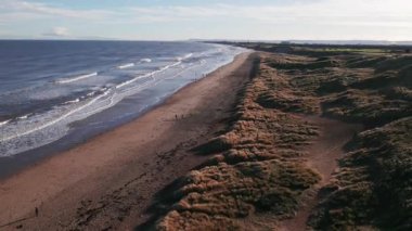 Drone geri uçuyor ve İngiltere 'nin Durham ilçesindeki muhteşem bir sahilde yavaşça kumulların üzerinden iniyor.